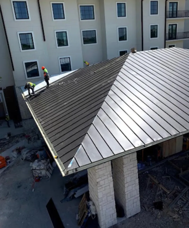Crew installing standing seam metal roof panels on a commercial project in Mira Monte